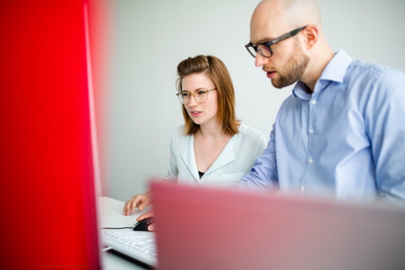 Zwei IT Young Professionals schauen auf einen Monitor